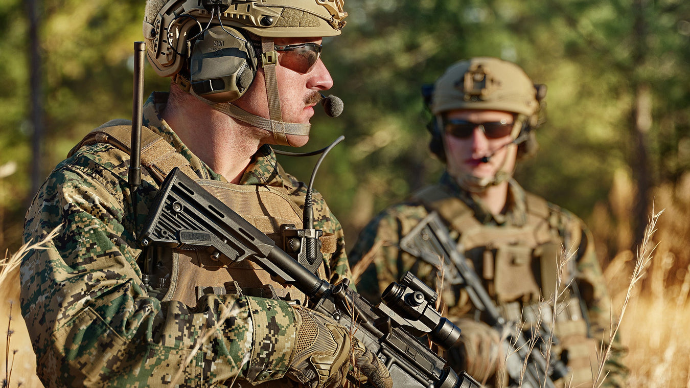 an image of two military personnel wearing camo and is on a field mission wearing 3m peltor comtac headsets and using it in action.