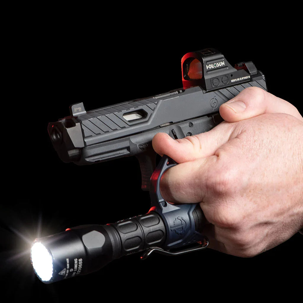 The image shows the Thrym Switchback 2.0 Deep Carry Flashlight Ling being used in action, attached to what looks like a 18650 body flash light as is being held while the product model is holding a small gun and the flashlight is being lit.