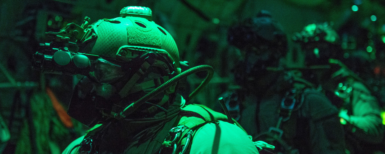 an image of a group of military personnel navigating the darkness with night vision equipment attached to their helmets