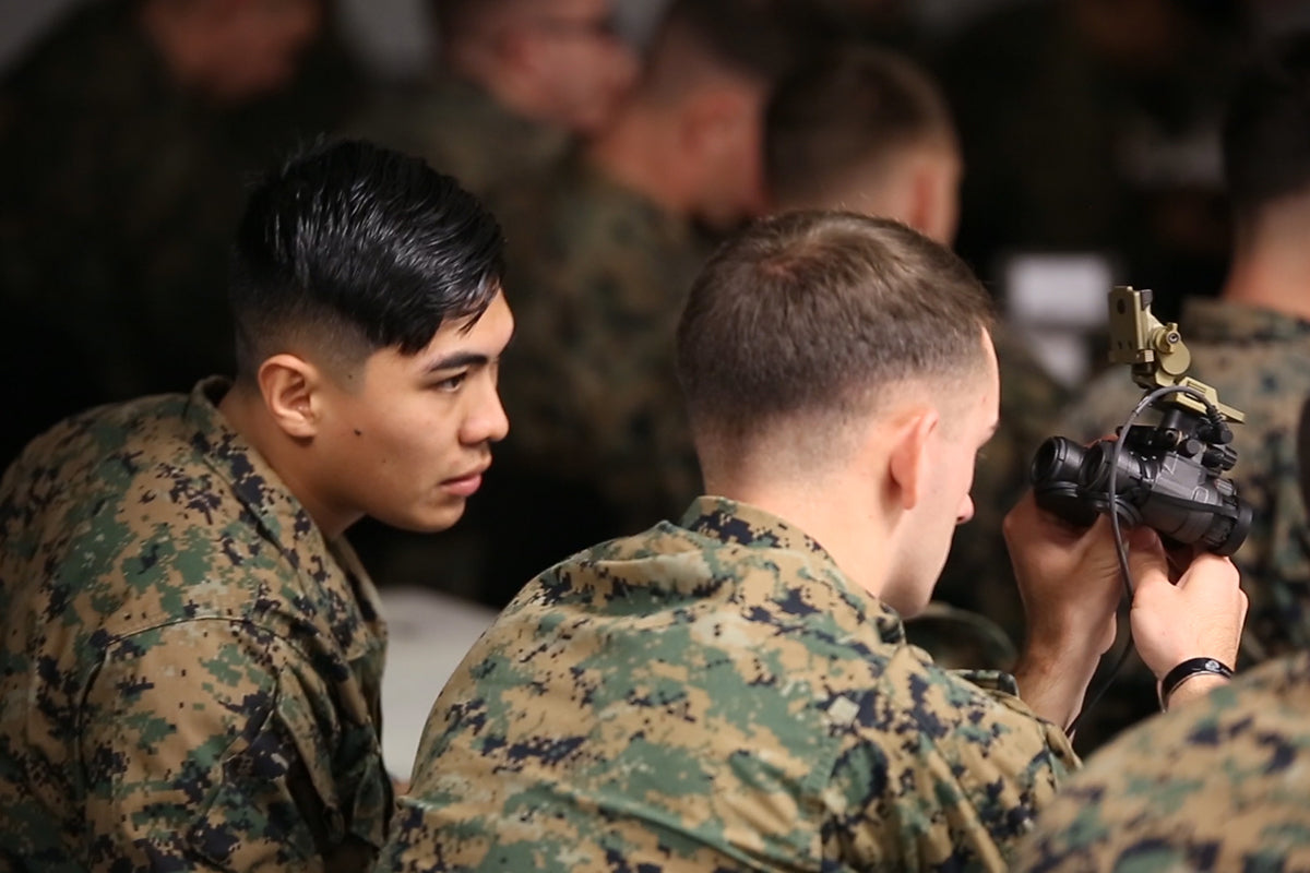 an image of two military personnel where one with brown hair is configuring the clip on thermal and the other military personnel with black hair is observing as this is being done