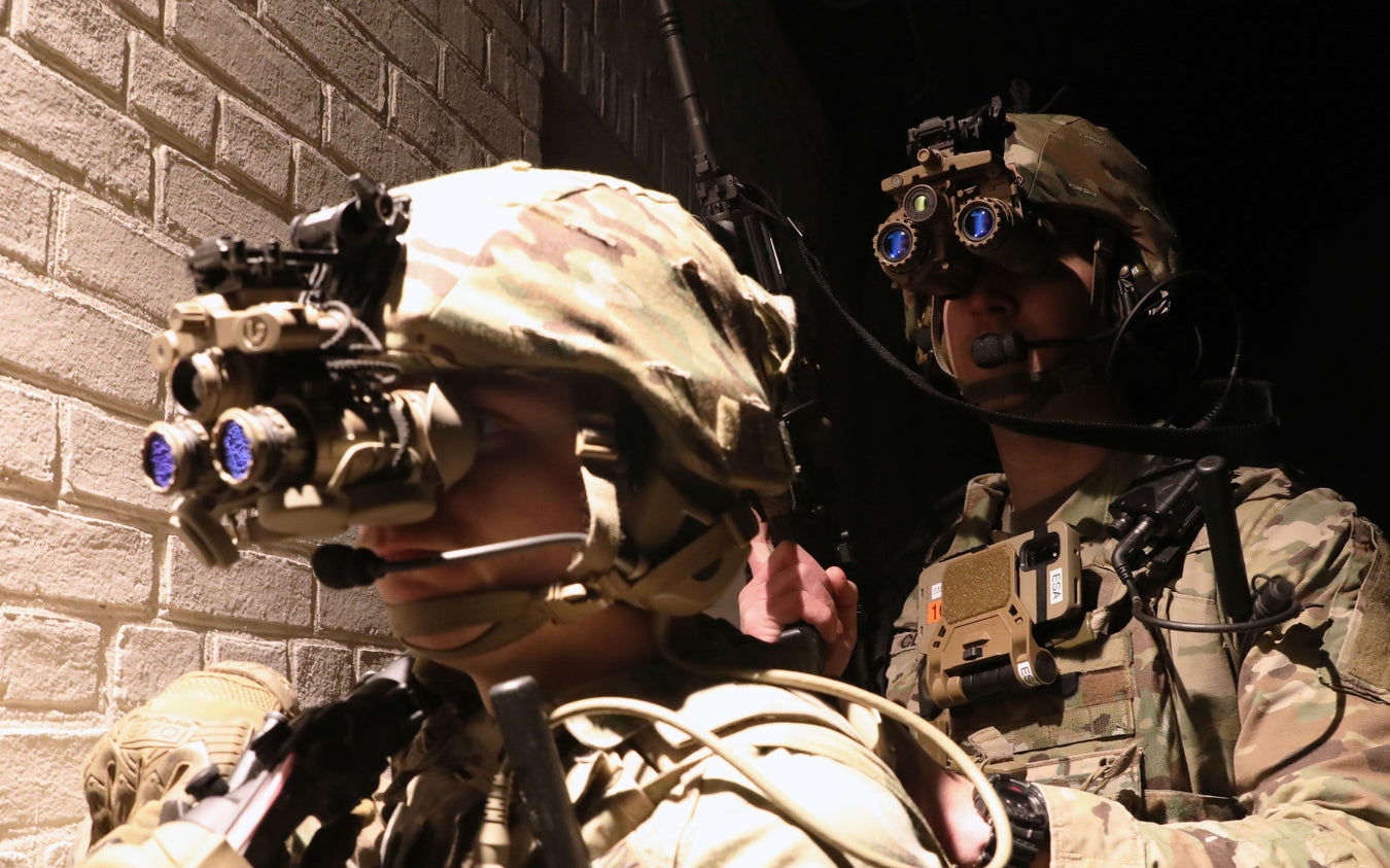 an image of two us army using what looks to be night vision sets that are mounted on their each of their helmets and are used for them to see as they are in action.