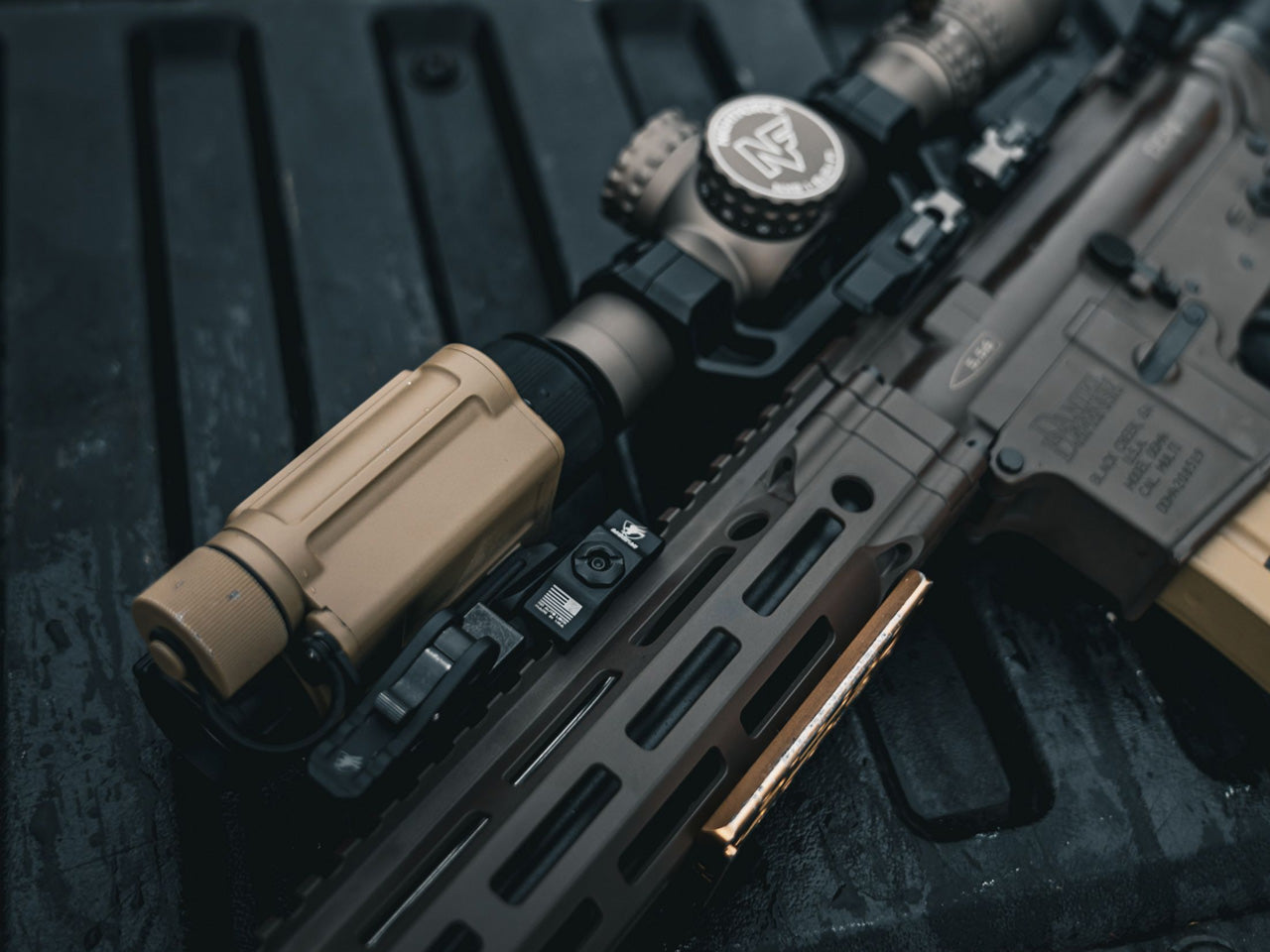 an image of the rh25 v2 clip on thermal that is being attached on an ar15 rifle and is being placed on top of what looks to be dark wooden planes.