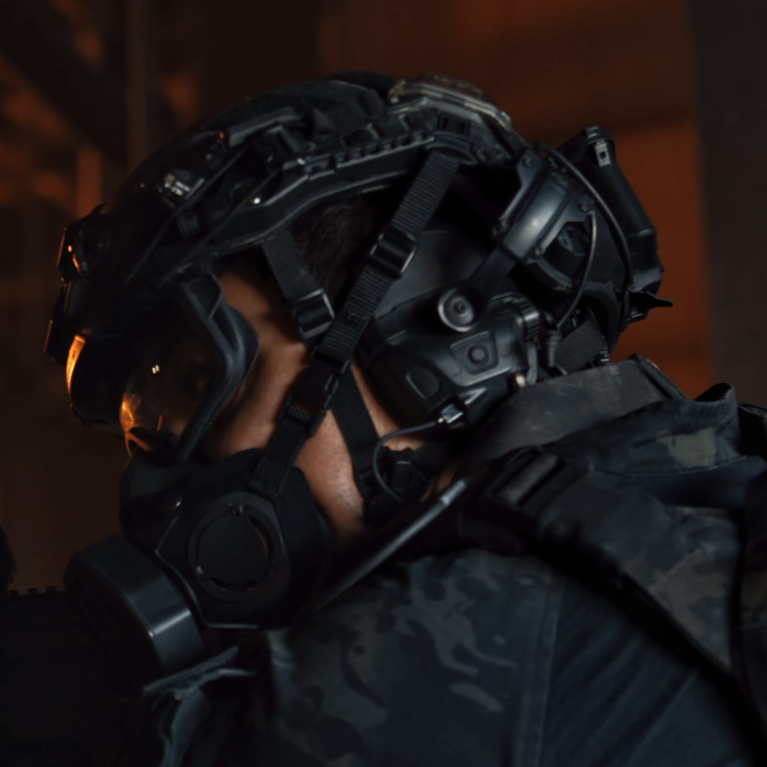 A SWAT operator wearing the new Ops-Core FAST XP Helmet System in black, demonstrating seamless integration with the Ops-Core ecosystem by utilizing AMP headsets on vented arms, a SOTR respiratory mask, and a Step-In Visor.