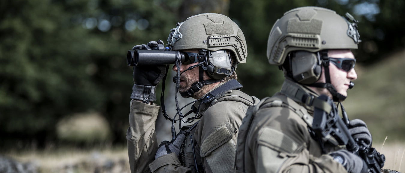 an image of two tactical military personnel where one is looking to be watching guard and another personnel is taking a look in his binoculars and both of these men are wearing the 3M Peltor Comtac VIII
