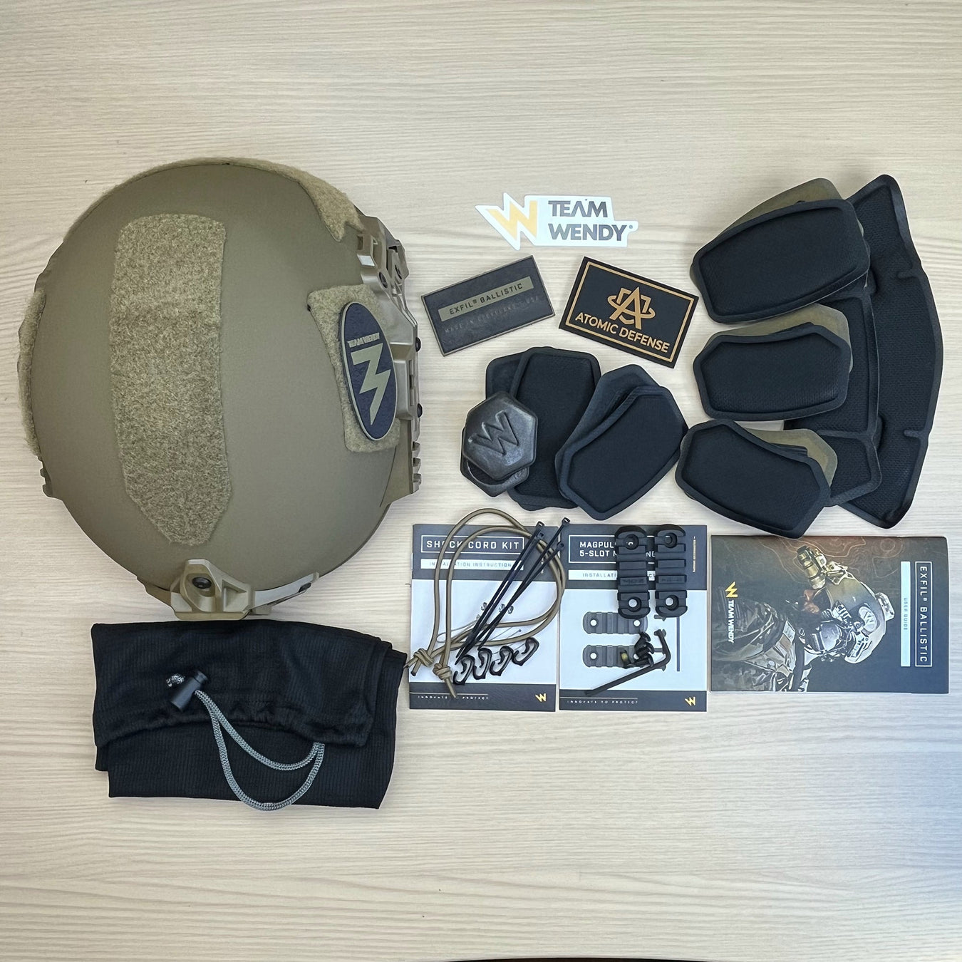 a tactical helmet placed on the floor with accessories, pads and other upgarde items around it