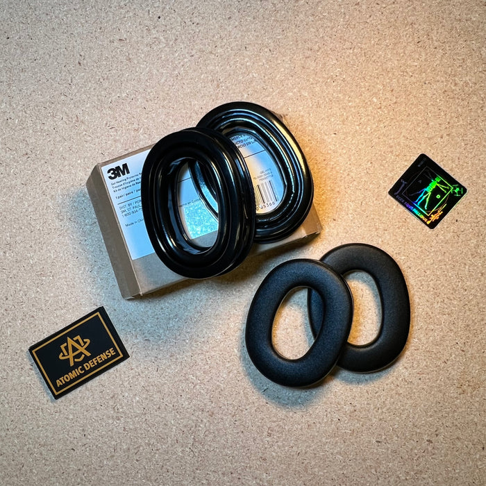 A cardboard box of 3M gel hearing protector replacement rings rests next to a pair of black gel ear cushions designed to upgrade the comfort of the Peltor ComTac VIII.