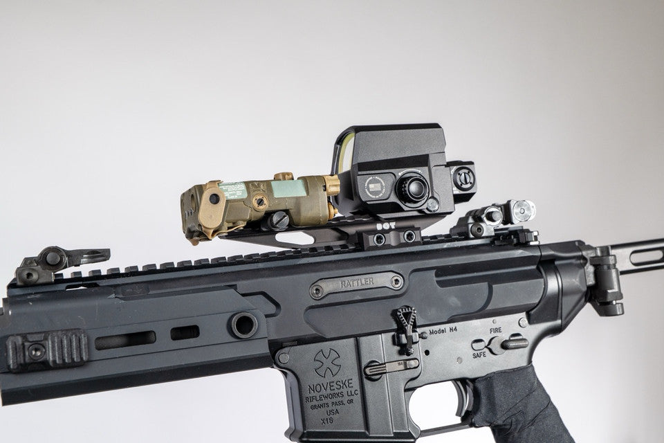 the image shows us the DORM EXT in the color black and is attached on a noveske rifle where the extension mount is clamped on top of it and what looks to be a holographic sight is also on top of the mount. 