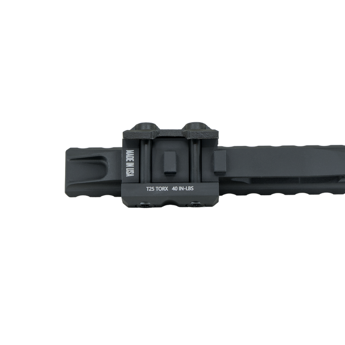the item showcases the DOT dorm EXT in the color black and is showcasing the understide view wher eit showcases "made in usa" and serial number brandings, as well as the mounting configuration on which the extension mount will be placed or attached on the user's rifle
