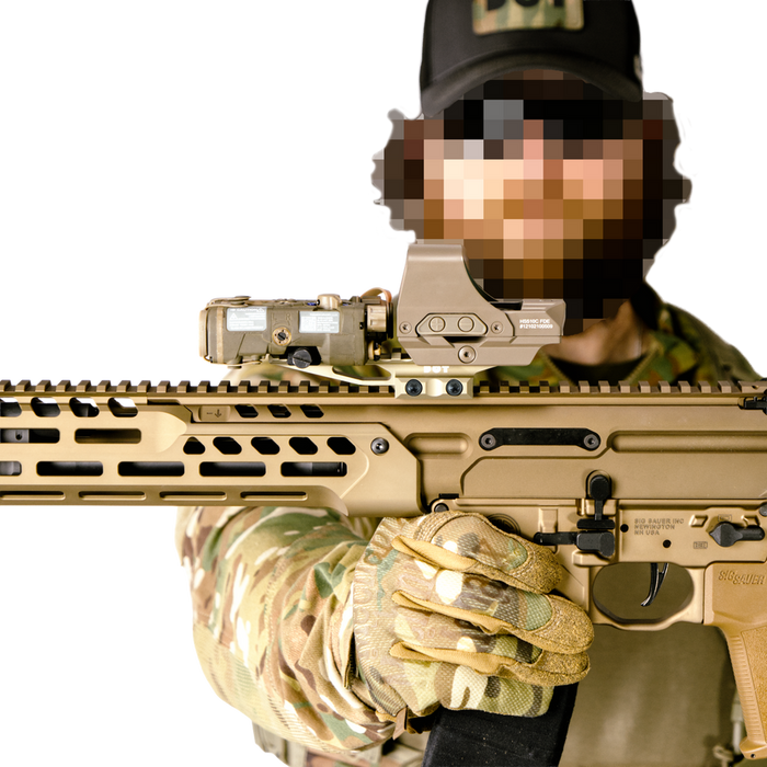 the image shocases a close up view of the DOT delta optic riser mount in the color fde or flat dark earth and is being mounted on top of a waepon with what looks to be a holographic sight also mounted on top of the mount itself, and the whole item is being held forward by someone who is wearing a camo outfit. 