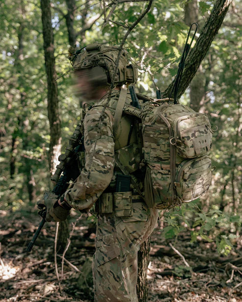 operator wearing a ROMAD comms backpack in multicam while scouting in the woods