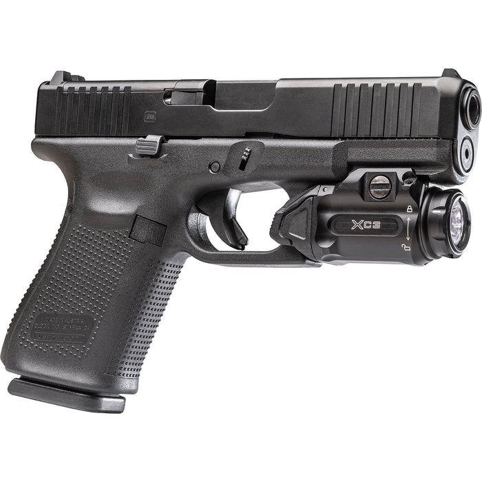 The Surefire XC3-B attached on a Glock 19 and is presented in the left side view where we can see the ridges of the gun and the Surefire weapon light's left side that has the lock instructions and brand name branded on 