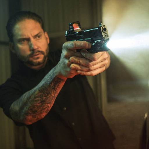 the surefire XC3-B pistol light attached on a gun and is being used and pointed by a man who had a tattoo on his arm