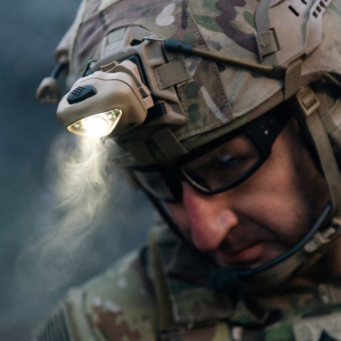 a close up shows a person wearing a helmet with a princeton tec vizz 550 rgb looking downwards