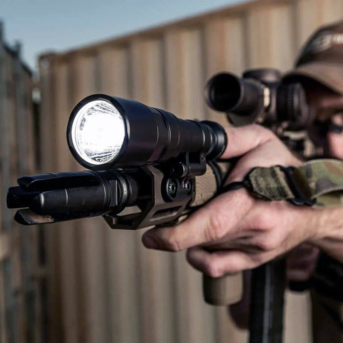 a marksman holding a rifle equipped with surefire scout light pro and scope aiming towards the left