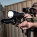 a marksman holding a rifle equipped with surefire scout light pro and scope aiming towards the left