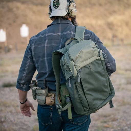 A shooter on the firing range wearing a Heather OD and Rudder Green Vertx Gamut CCW Tactical Backpack during training.
