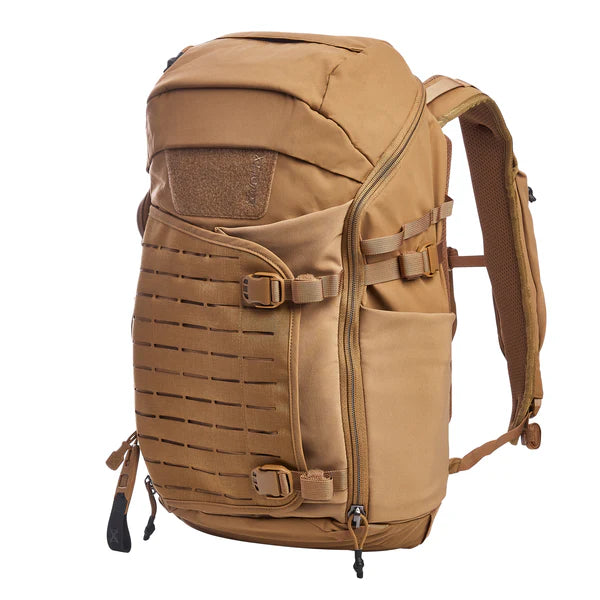 A side-angled view of the Vertx Siege 25L tactical backpack in Coyote features the expandable external pouch and laser-cut MOLLE panel in the foreground with a bottle pouch on the side.