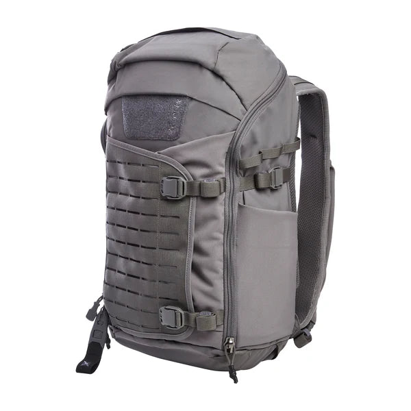 A side-angled view of the Vertx Siege 25L tactical backpack in Wolf Grey shows the expandable external pouch and laser-cut MOLLE panel in the foreground with a bottle pouch on the side
