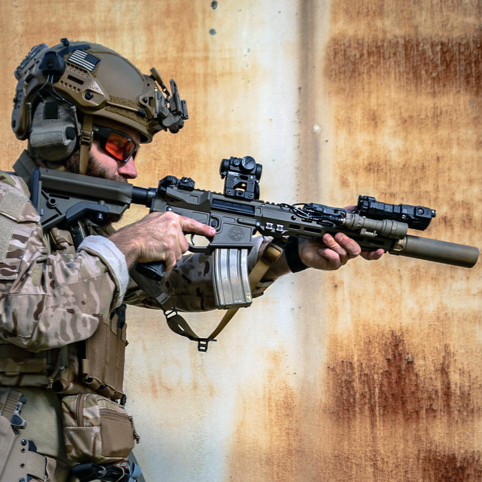 a special forces operator is shown holding a rifle equipped with surefire mini scout light pro and wearing tactical gear against a weathered backdrop