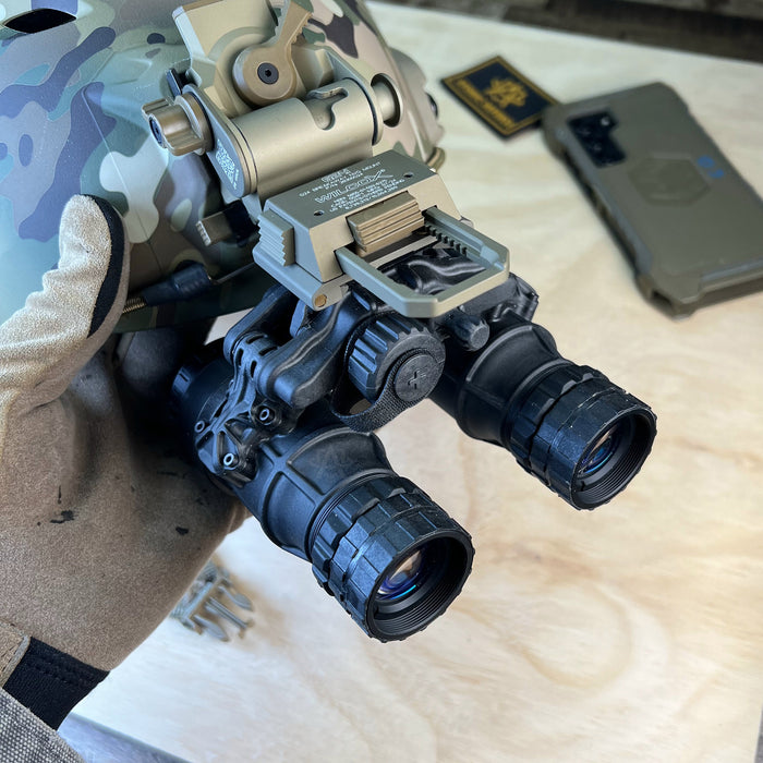 A left side angled view of the professional black act in black dtnvs manual gain system securely attached to a ranger green wilcox g24 mount on a durable team wendy bump helmet, demonstrating a complete tactical headborne setup.