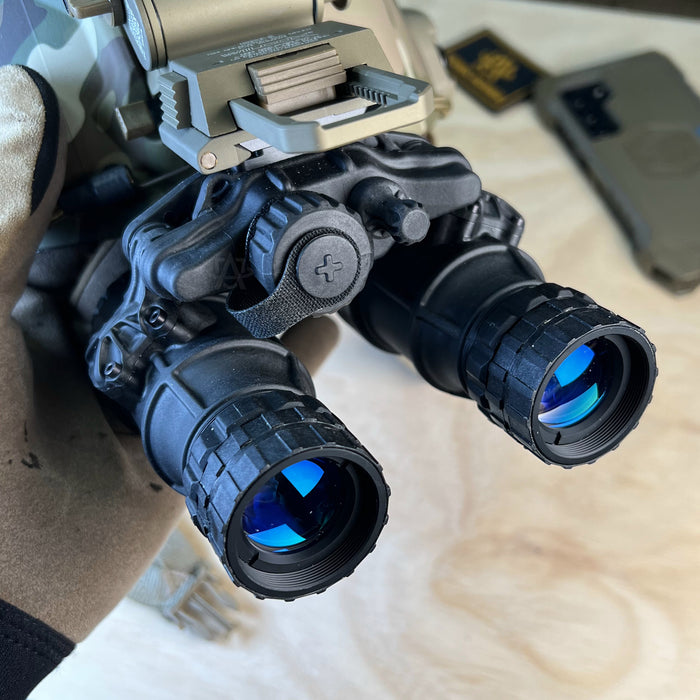 A detailed close-up shot of the act in black dtnvs mg for sale in black finish, mounted on a ranger green Wilcox G24 and a Team Wendy bump helmet, with the waterproof battery compartment clearly visible in the foreground for easy operator access.