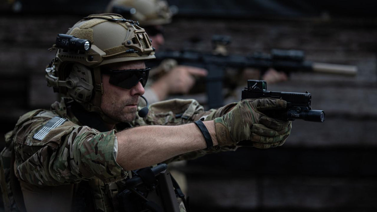 Aimpoint COA red dot sight mounted on a pistol during a tactical shooting exercise, shown alongside a weapon-mounted flashlight.