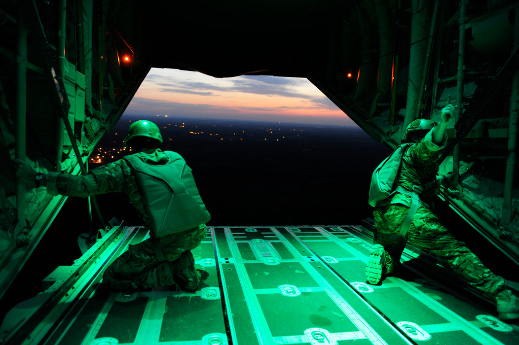 Two airborne operators preparing an aircraft compartment with the CORE Survival Portable Jump Light illuminated red to indicate "not ready" status.