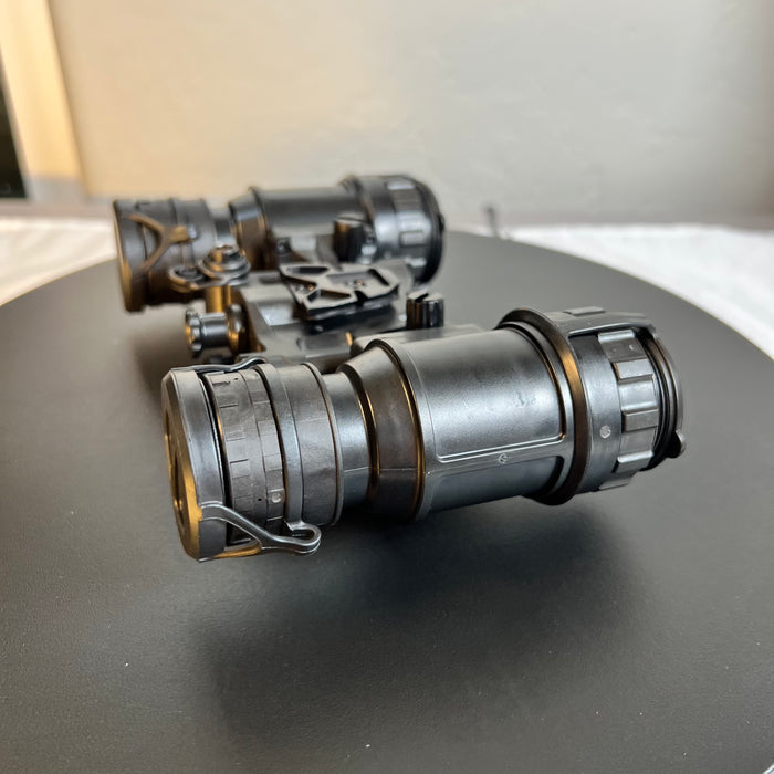 A side right view of the an/pvs-31d night vision goggles shows the articulating housing in an open position. Both the front and back lenses are covered with protective caps to keep the Gen 3 white phosphor thin-filmed tubes safe from light damage.