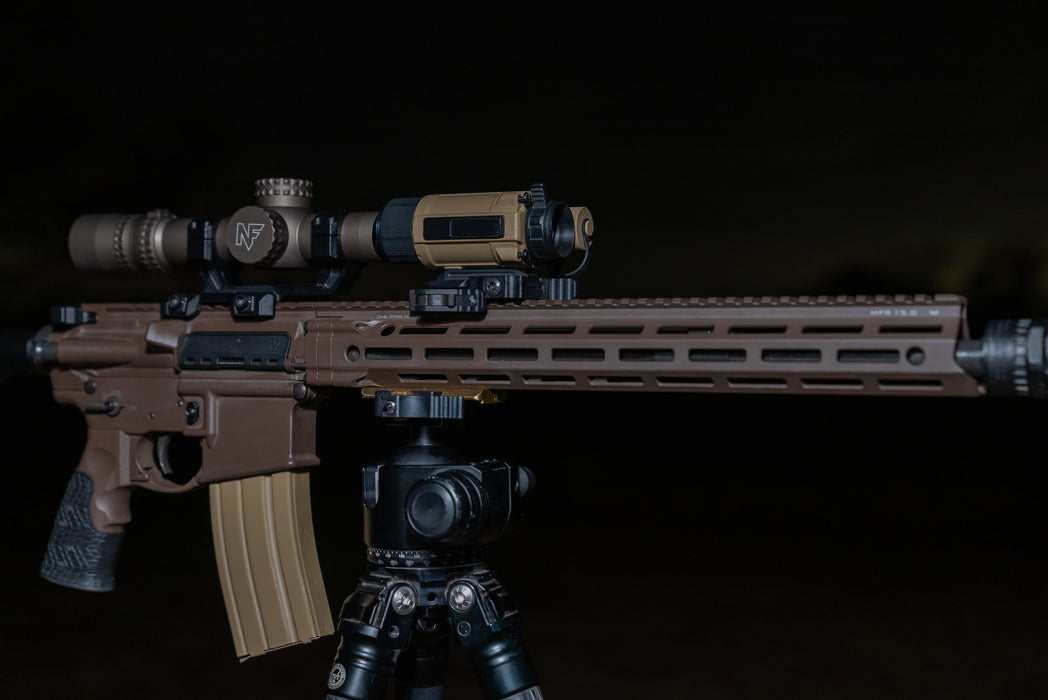 rh25 v2 thermal Optimized Alt Text: An AR-15 rifle setup at night, featuring an rh25 v2 thermal device mounted as a clip-on sight in front of a Nightforce magnified scope.