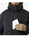 A close-up view of the black jacket showing a person placing a map into one of the insulated chest pockets, which use high-performance Coreloft synthetic insulation to keep essential mission items protected and hands warm.