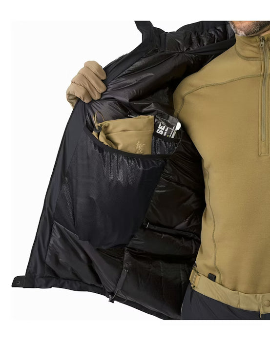 A person opens the black Arcteryx jacket to show a tan beanie tucked into the large internal mesh pocket, revealing the quilted inner lining that holds the Coreloft synthetic insulation in place for maximum warmth.