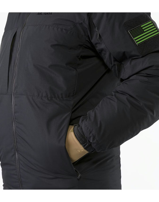 A side view of the black Arcteryx Cold WX Jacket showing a person tucking a gloved hand into the insulated lower torso pocket, which is designed to keep hands warm during cold weather operations.