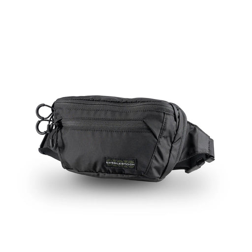 A sharp right-side angled view of the black Eberlestock Bando Bag, showcasing its compact shape and durable nylon construction that sits flush against the body for a low profile.