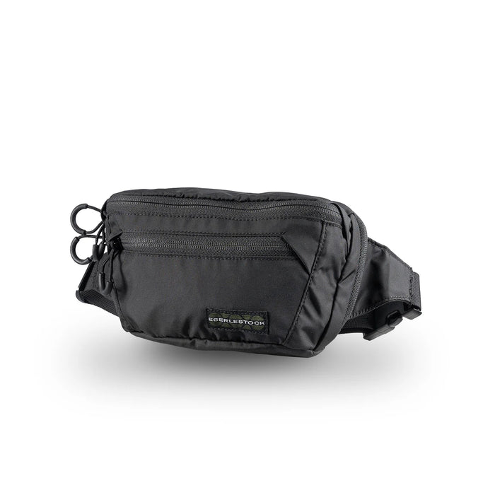 A sharp right-side angled view of the black Eberlestock Bando Bag, showcasing its compact shape and durable nylon construction that sits flush against the body for a low profile.