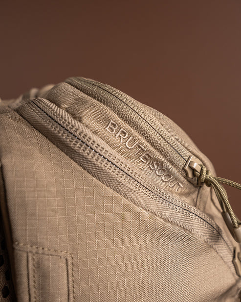 A close-up shot of the upper section of the Brute Scout Daypack, clearly showing the "Brute Scout" model logo embroidery and the heavy-duty zippered top compartment designed for organizing high-priority scouting essentials.