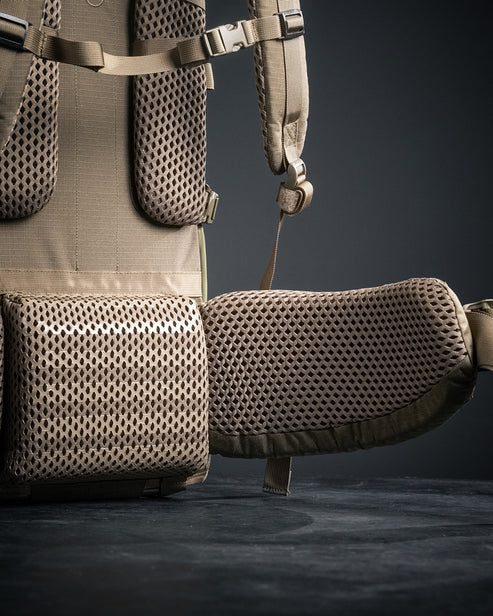 A detailed close-up shot of the heavy-duty hip belt on the Brute 4500 Load Hauling Pack, highlighting the high-density ergonomic padding and reinforced stitching designed to comfortably support 100+ lb loads.