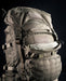 A detailed close-up of the upper front storage pouch on the exterior of the green Eberlestock Mission Ruck, highlighting its rugged material and accessible zipper compartment.