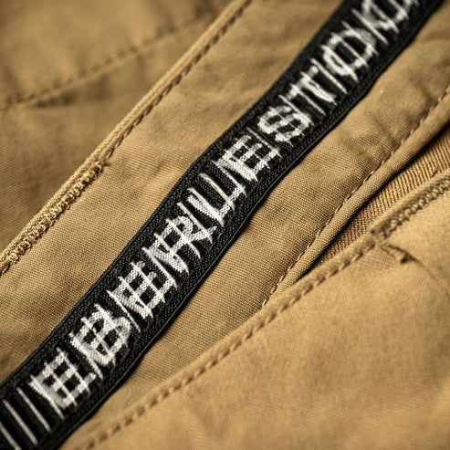 A close-up view of the waistband on the Eberlestock Deadwood, featuring the non-post button closure designed to prevent digging while wearing a heavy pack belt.