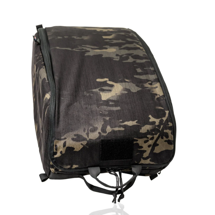 A closed military helmet bag shown in a dark Multicam Black camouflage pattern, designed with a soft padded exterior, a front velcro patch area, and sturdy bottom loops for easy handling.
