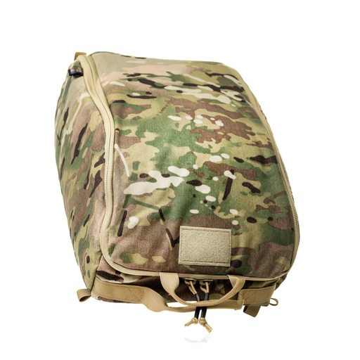 A closed, padded tactical helmet bag in a classic Multicam camouflage pattern, featuring a top zipper closure, a blank velcro patch panel for identification, and durable pull tabs at the base.