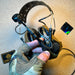 Coyote brown Peltor ComTac VIII tactical headset showing the flexible boom microphone attachment, integrated communication cables, and contoured earcups against a tan textured background.