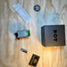 the DOT EHS-1 Holographic Sight placed outside of its box and is turned on wiht its battery pack, item box and atomic defense patches around it with all items placed on a wooden desk