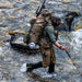 A hunter wading through a small river, showcasing the water-repellent properties of the Eberlestock Camas Pro Long Pants as the fabric actively sheds moisture.