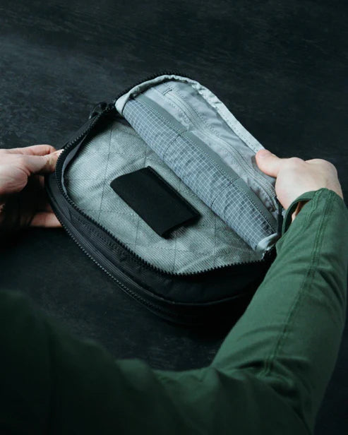 the image showcases the eberlestock ade flex micro in the color black and is showcasing the product's velcro-in pistol retainer in one of its pockets that will secure the user's pistols 