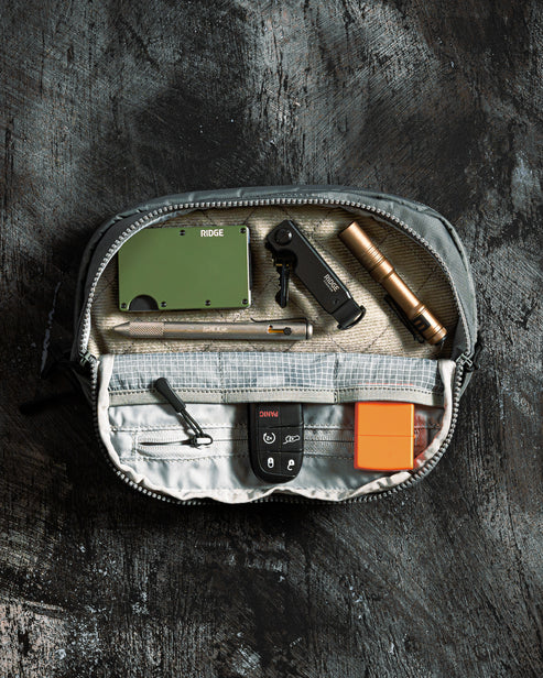 the image shows the eberledstock fade flex micro in what looks to be the steel variant and also shows a visual of how the product would be like when used and has a lot of small items inside; it highlights the three pockets it has on the flap side as well as the other zipper-closed compartments in the product.