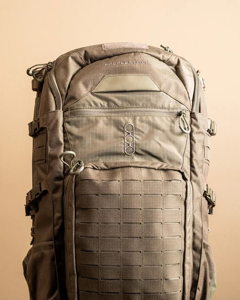 A detailed close-up of the front of the Eberlestock Spectre 50L Military Backpack featuring the embroidered Eberlestock logo and rows of heavy-duty MOLLE webbing for attaching extra gear.