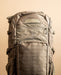 A detailed close-up of the front of the Eberlestock Spectre 50L Military Backpack featuring the embroidered Eberlestock logo and rows of heavy-duty MOLLE webbing for attaching extra gear.