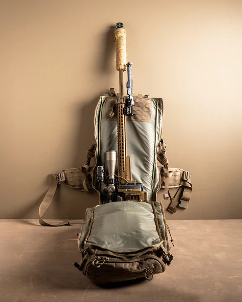 A frontal shot of the Eberlestock Spectre 50L Military Backpack with the scabbard compartment open, showing a large sniper rifle completely secured inside the padded RAID system.