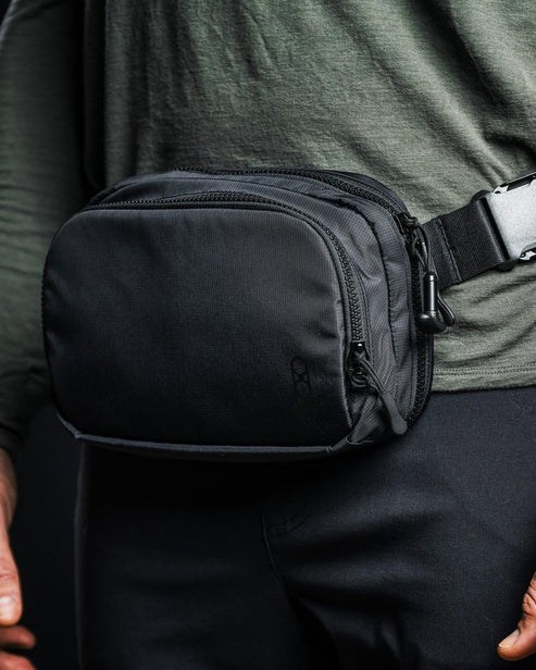 an image of the eberlestock fade flex micro in the color black and is being worn by a product modeler on his waist.