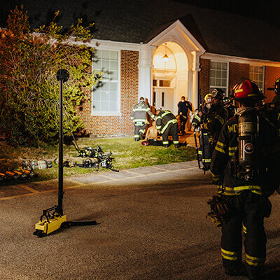 Firefighters using the Streamlight Portable Scene Light to illuminate the front of a house during night operations